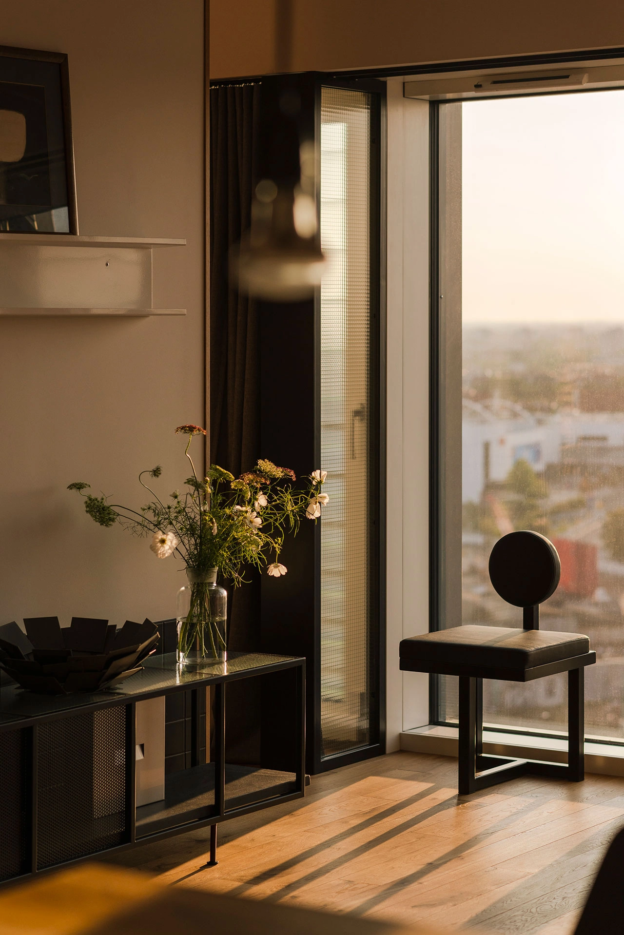 partial angled view of modern living room corner with black chair and black console