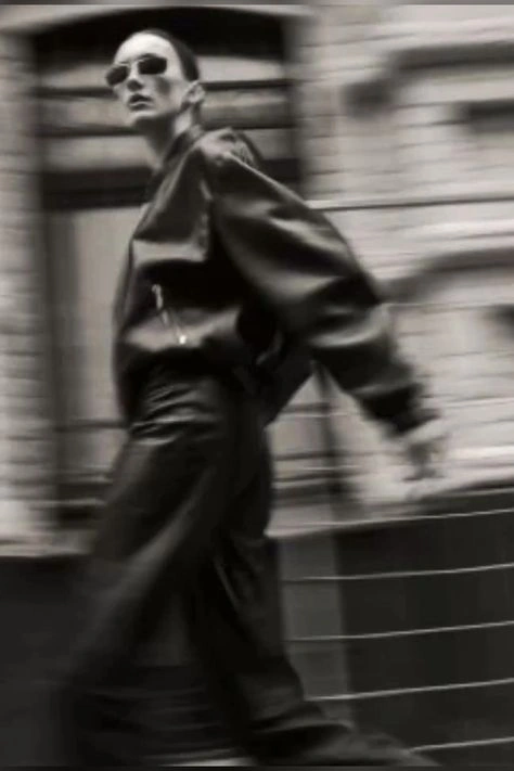 This may contain: a man walking down the street in black and white