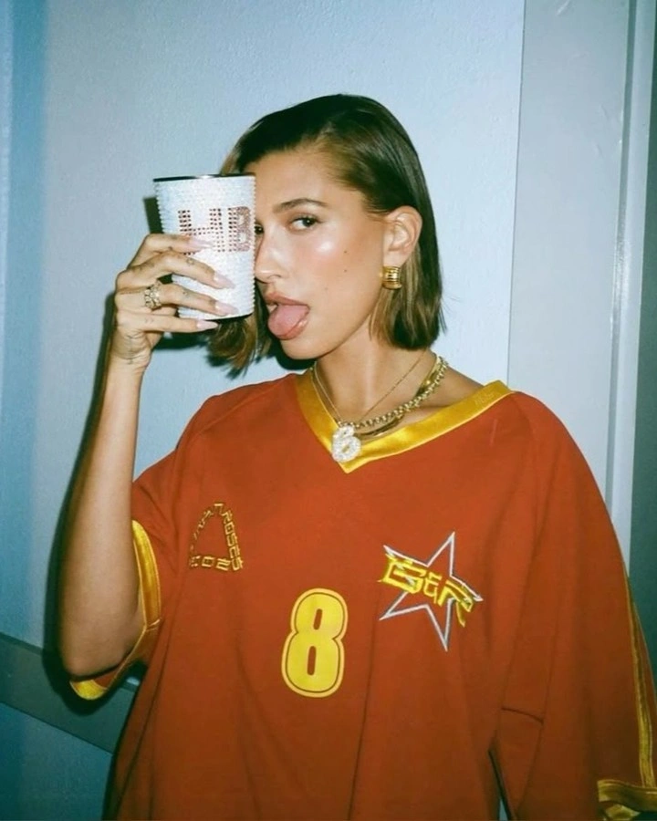 Photo by Fan Page || Hailey Rhode Baldwin Bieber on October 21, 2024. Pode ser uma imagem de 1 pessoa, maquiagem, pelo, camisa, gravata de caubói, toca-fitas portátil e texto.