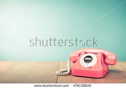 Retro pink telephone front mint green wall background. Old style filtered photo