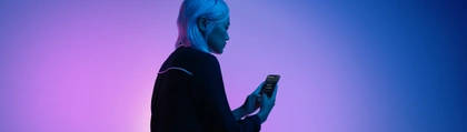 A woman holding a cell phone with Dark Mode enabled.