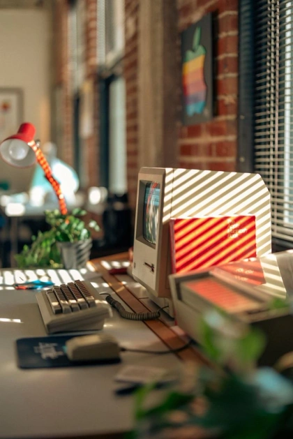 This may contain: an old computer sitting on top of a desk next to a plant and window sill